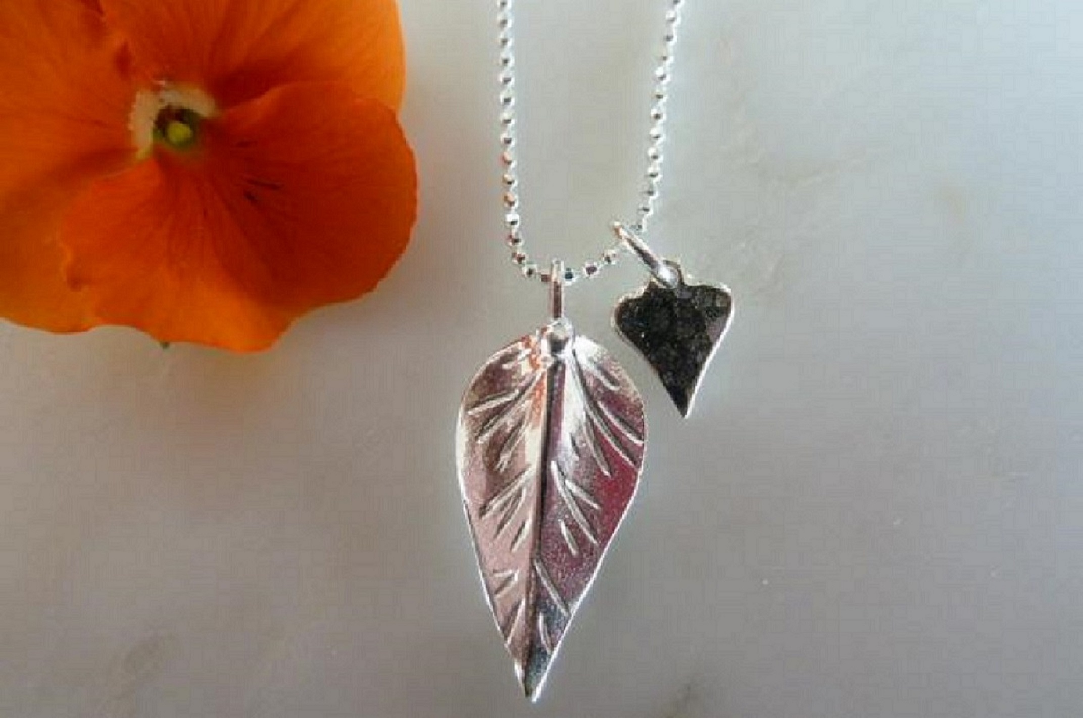 Jewellery. A silver leaf and heart necklace.